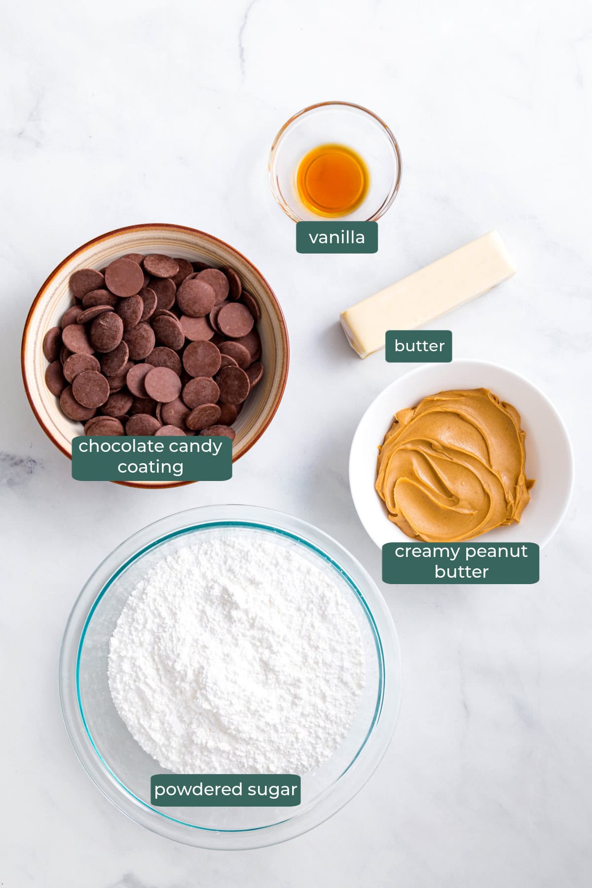 The five ingredients for homemade peanut butter eggs in bowls on a white countertop.