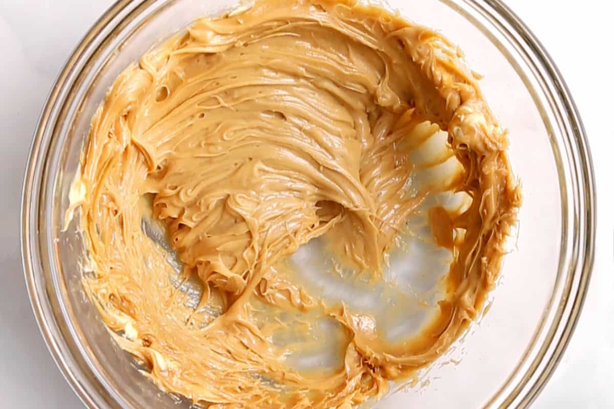 the peanut butter, softened butter and vanilla mixed together until smooth in a glass bowl on a white countertop.