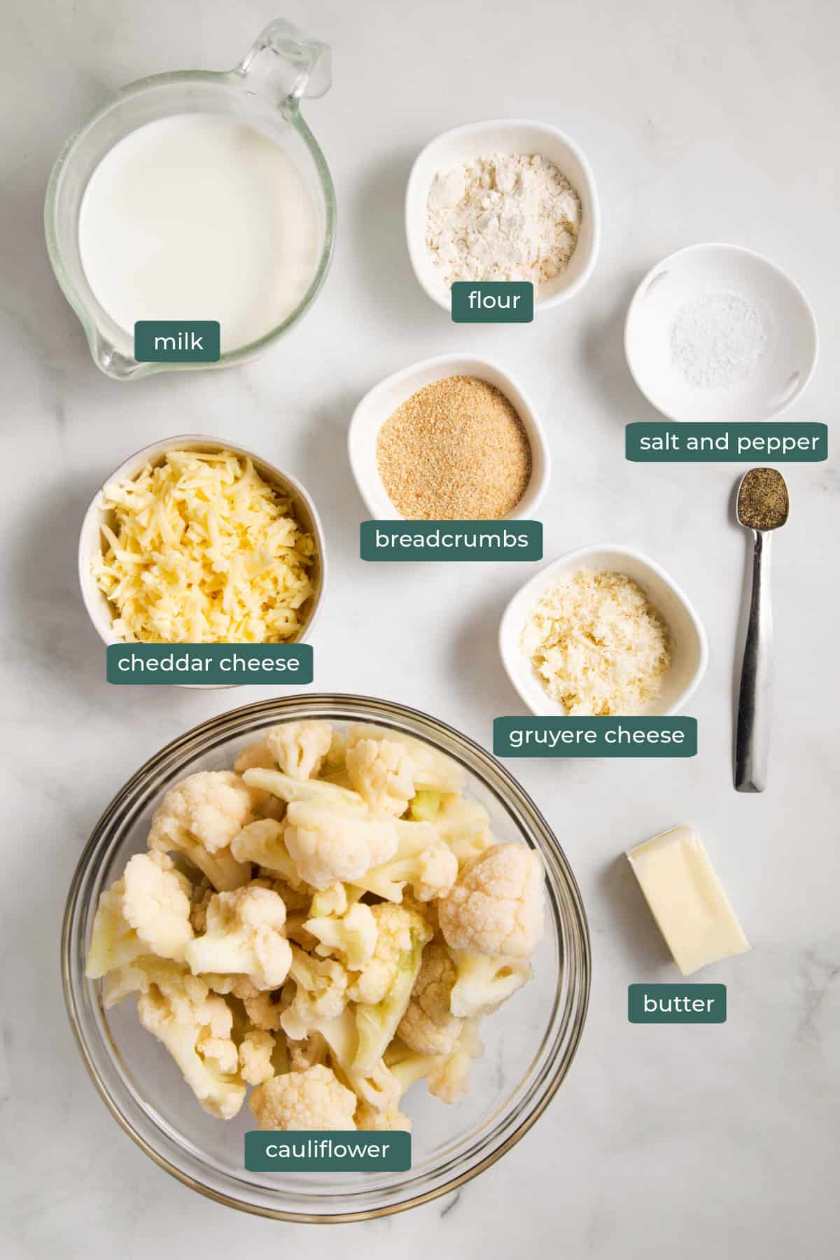 All of the ingredients for cauliflower au gratin in bowls on a countertop.