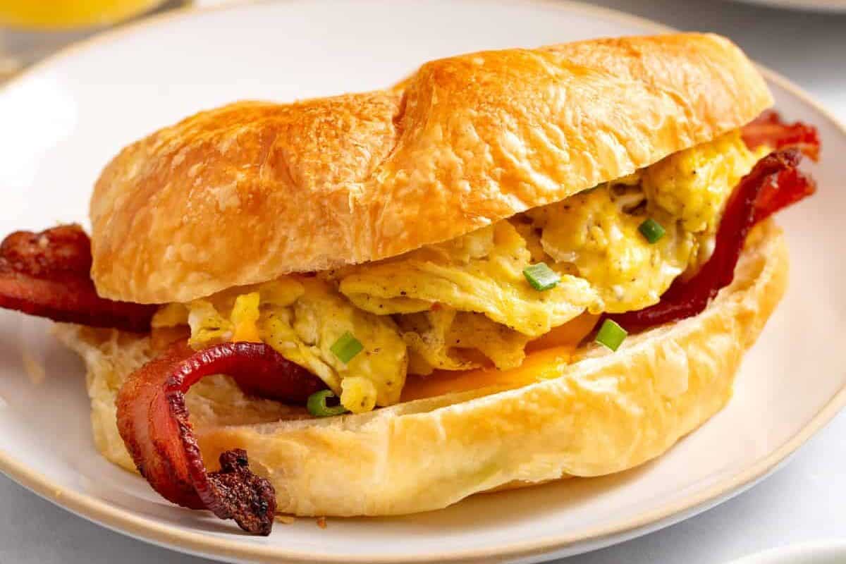 A croissant breakfast sandwich on a plate.