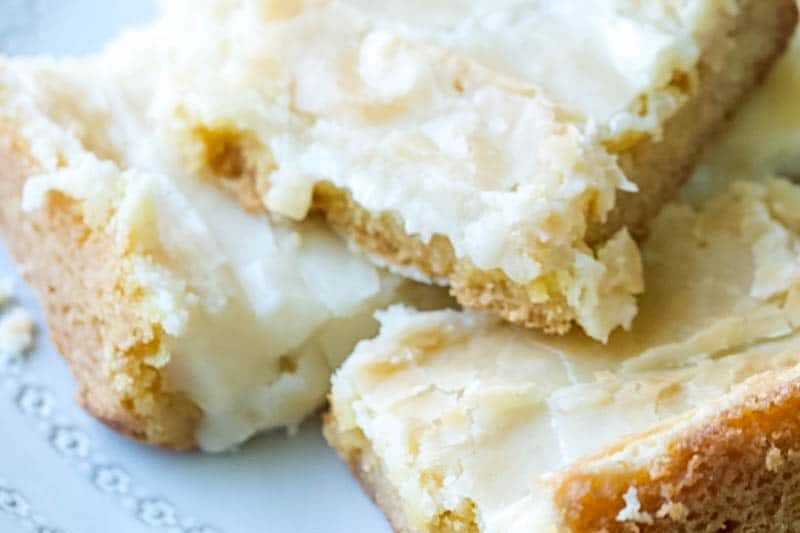 close up of ooey gooey cake bars stacked on a plate