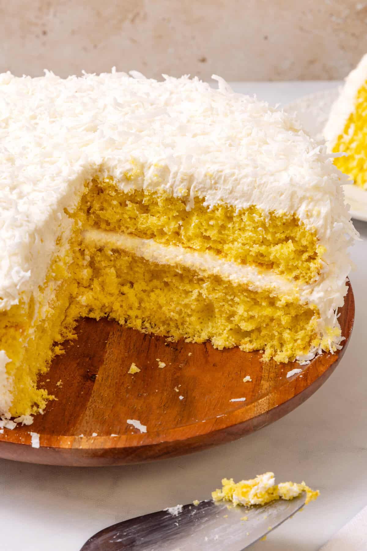 lemon coconut layer cake with slice cut out. 