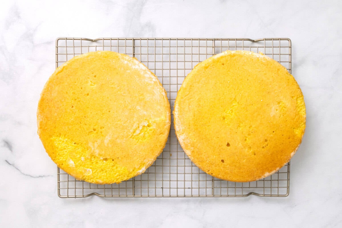 Two lemon cake layers on cooling rack.
