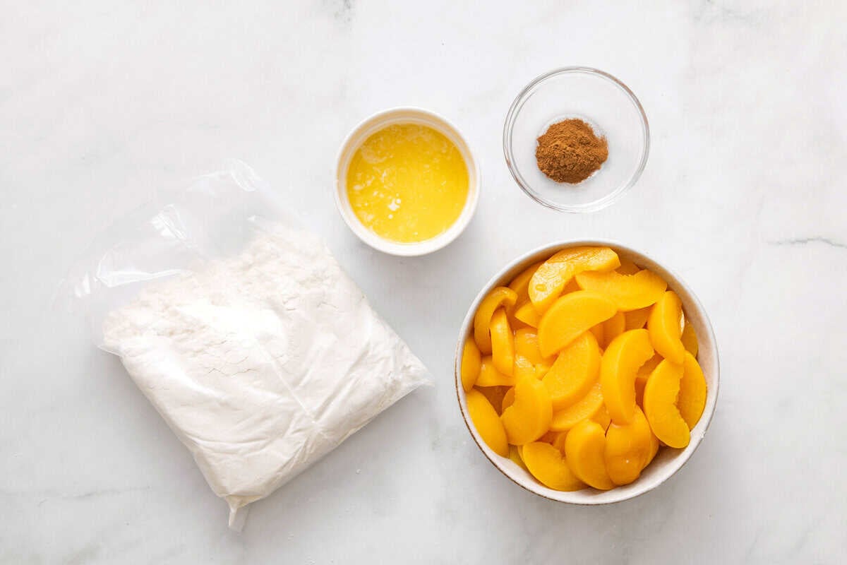Ingredients for peach cobbler with cake mix, including peaches, cake mix, butter, cinnamon.