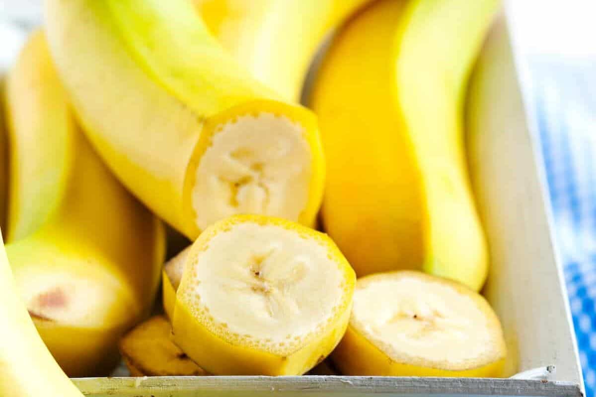 Bananas in a dish, with one cut into slices.