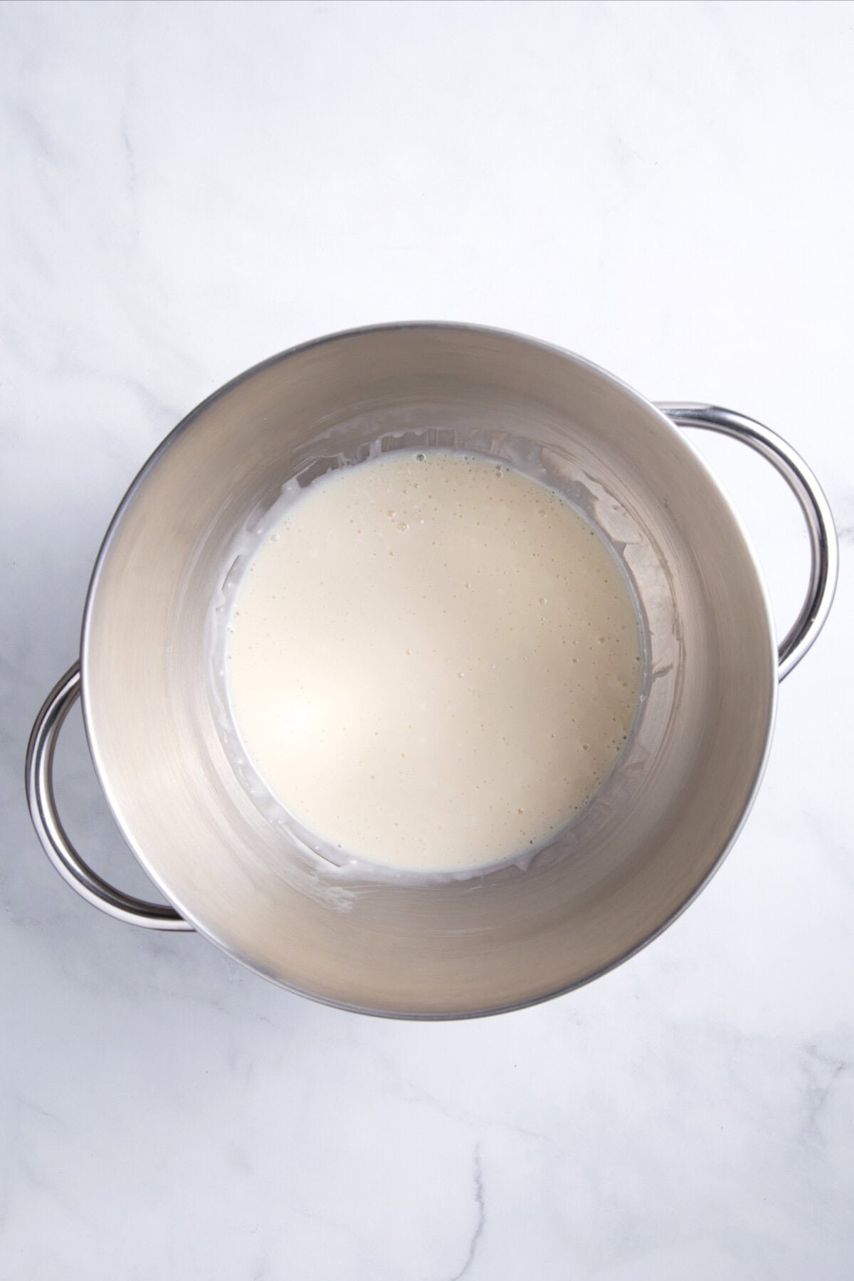 Cream cheese and condensed milk beaten in bowl.