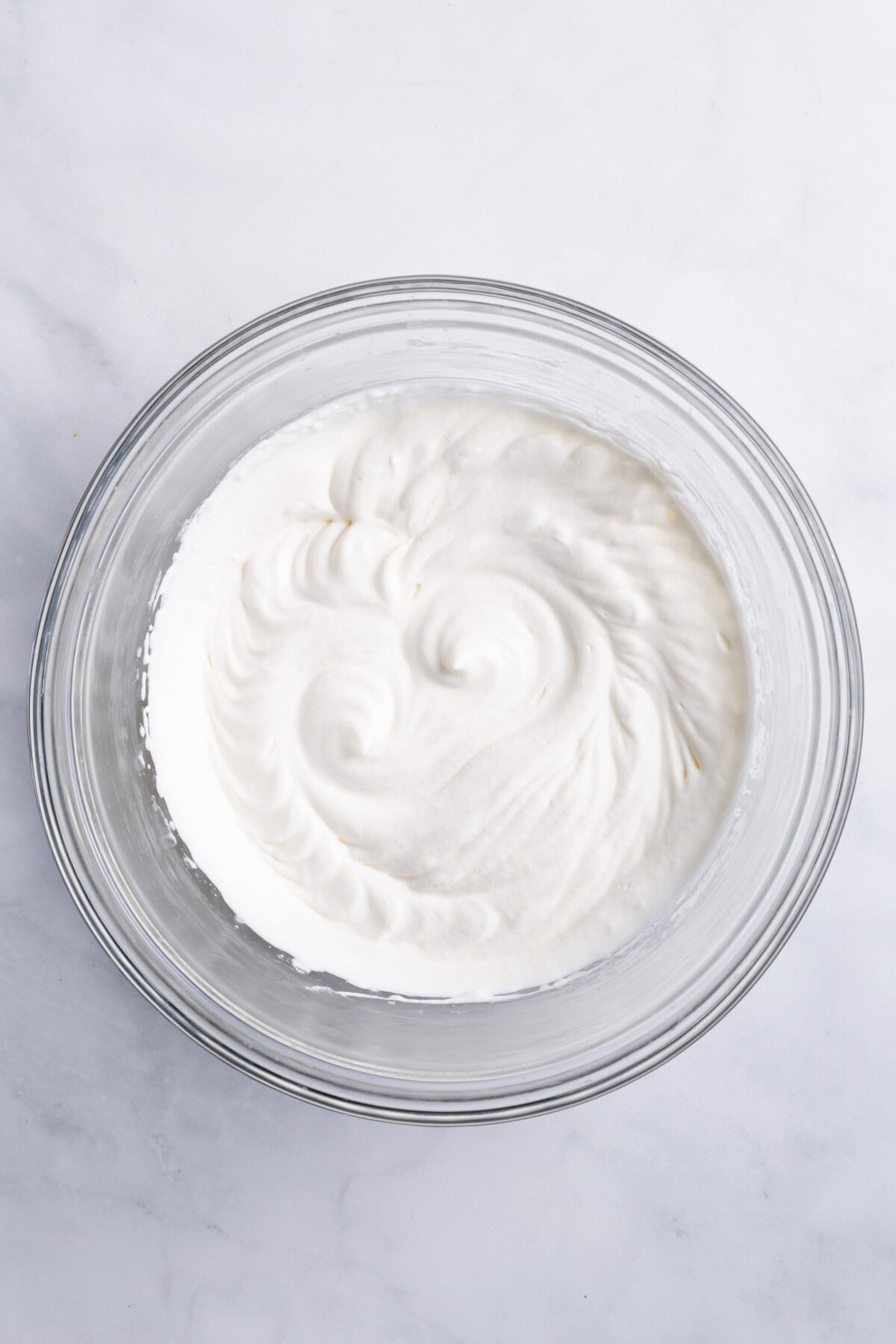 Whipped cream in glass mixing bowl.