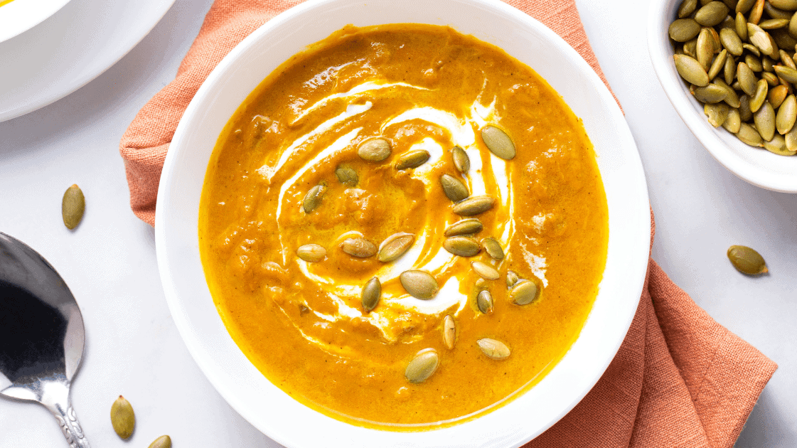 A bowl of pumpkin soup topped with pepitas.