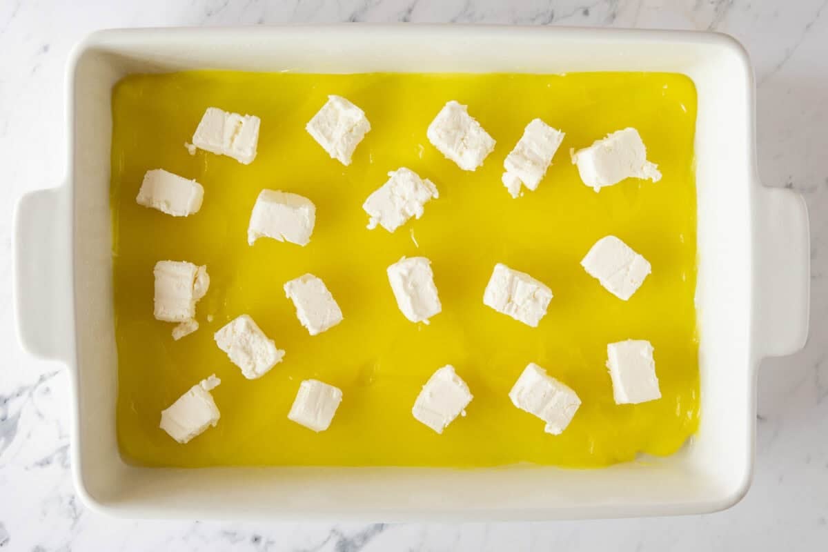 Cream cheese cubes on top of lemon pie filling in pan.