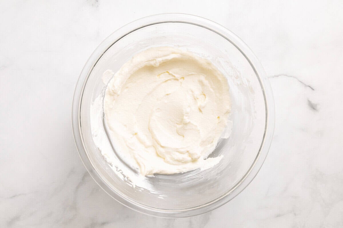 Overhead view of whipped cream in glass mixing bowl