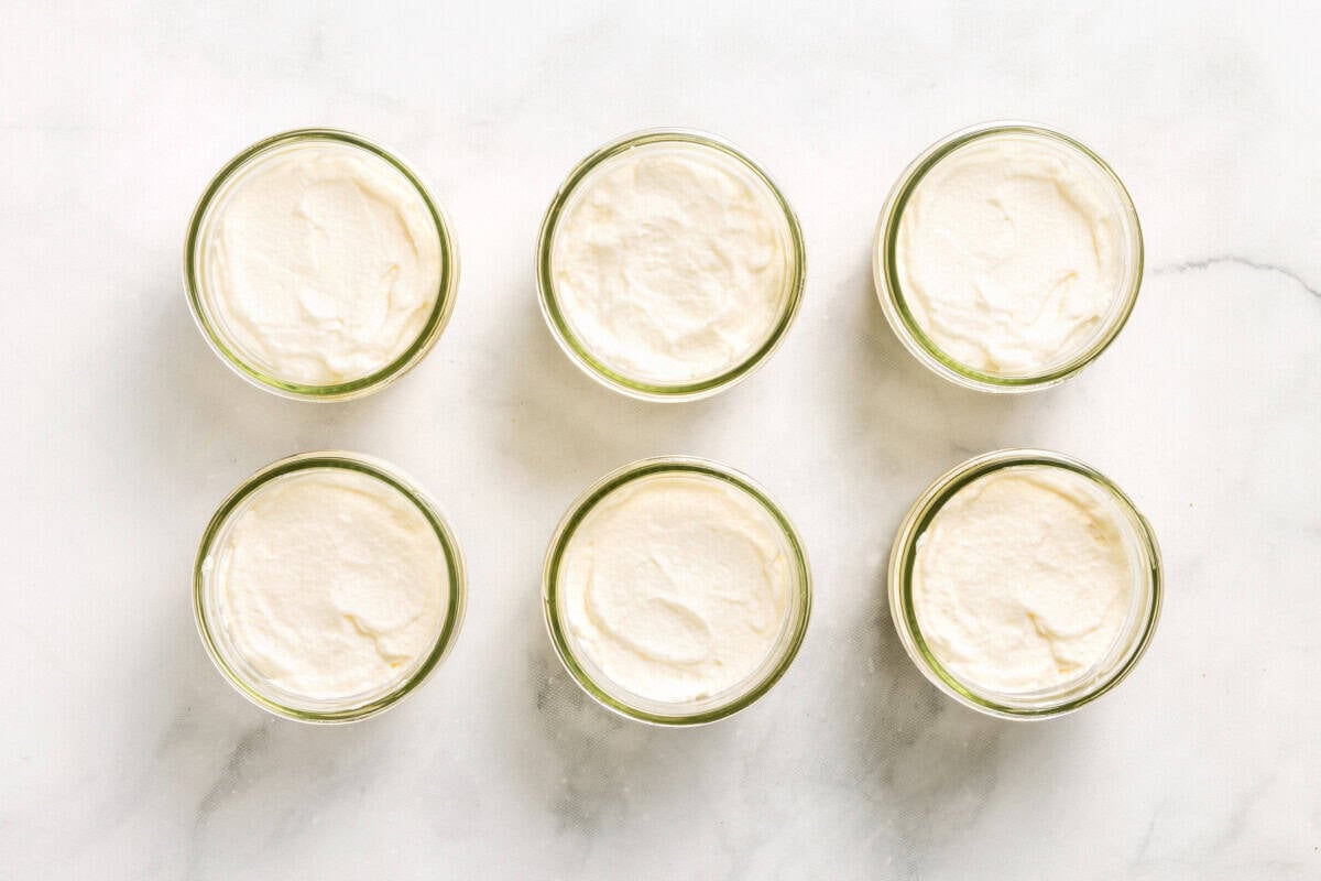 Overhead view of coconut cream pie parfaits in jars with whipped cream on top