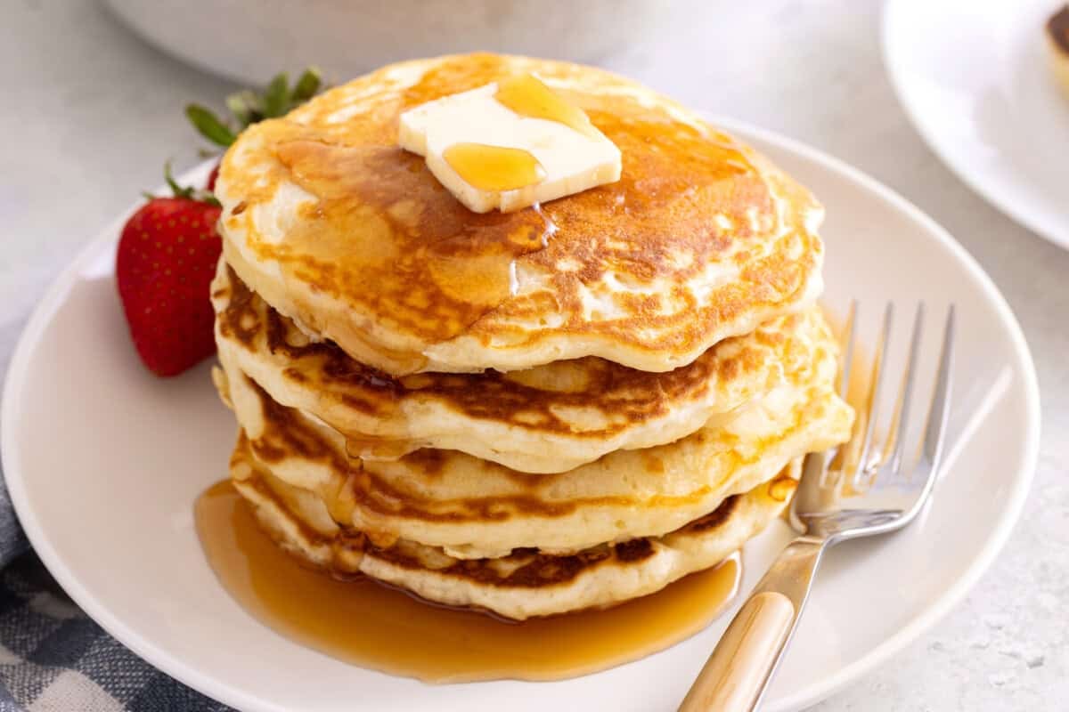 Stack of fluffy pancakes on plate.