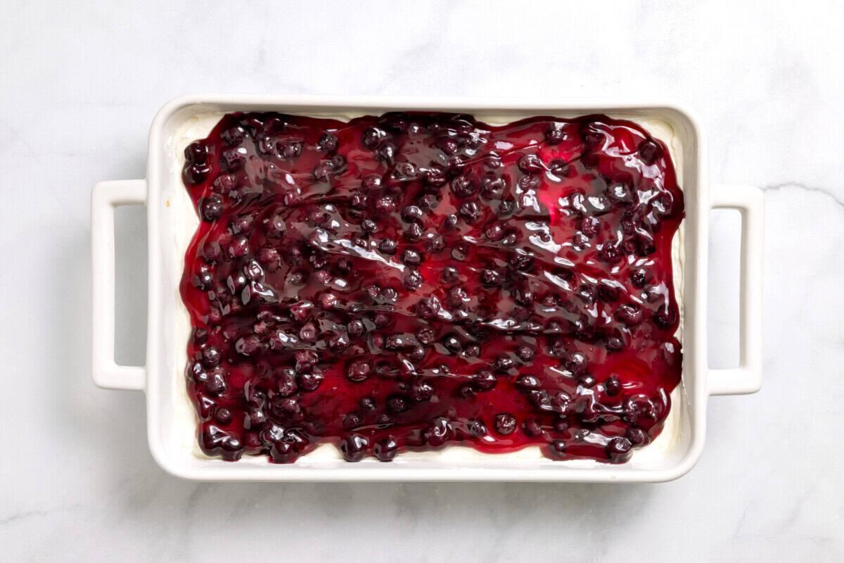 Overhead view of blueberry pie filling added to lemon blueberry delight