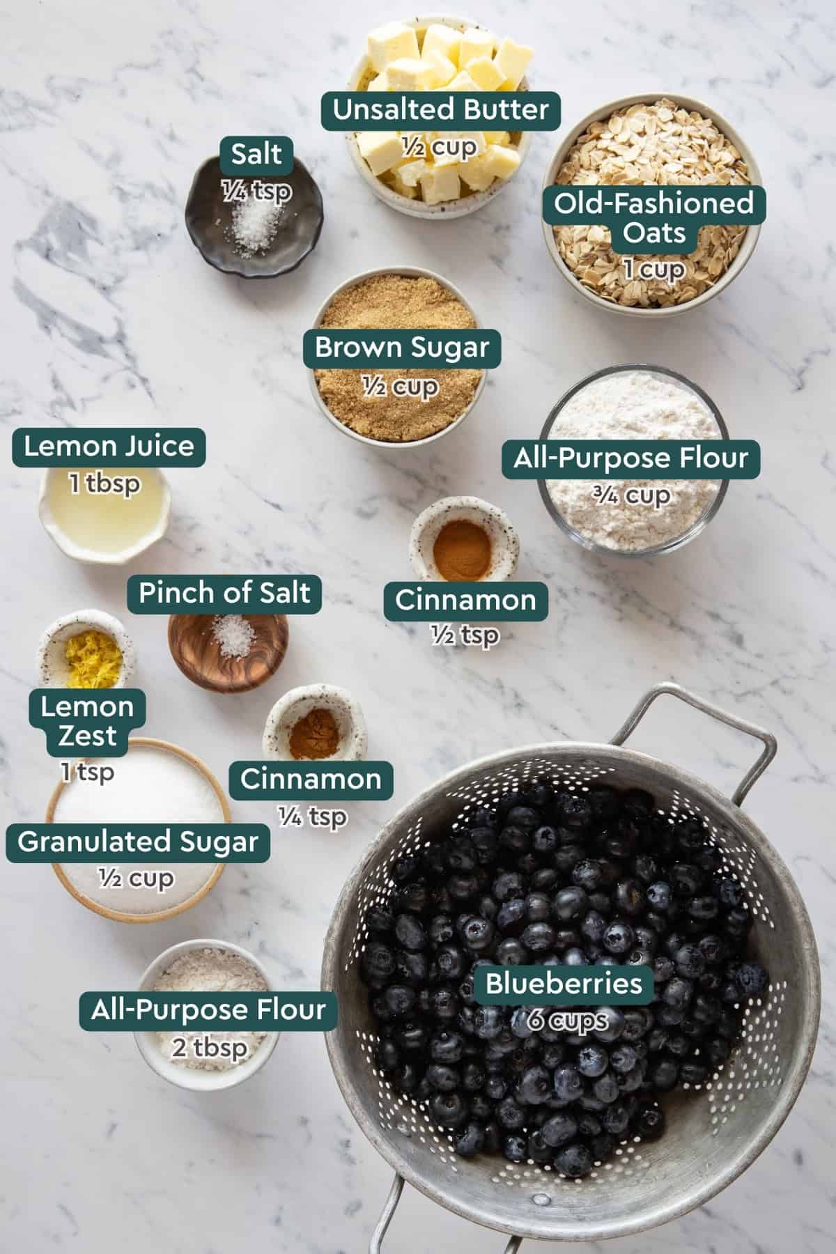 Ingredients for blueberry crisp, including butter, oats, salt, sugar, flour, lemon juice, cinnamon, lemon zest, sugar, blueberries.