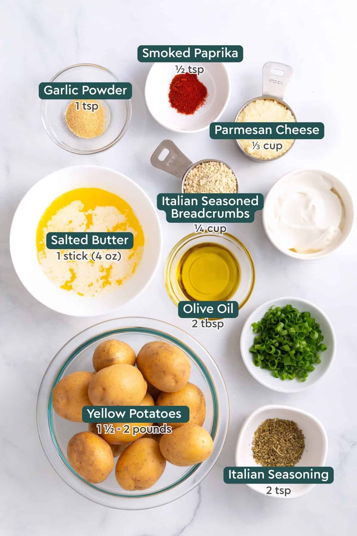 Ingredients for crispy parmesan potatoes, including seasonings, parmesan, breadcrumbs, butter, olive oil, italian seasoning, potatoes.