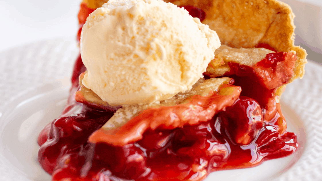 slice of cherry pie with a scoop of vanilla ice cream on top