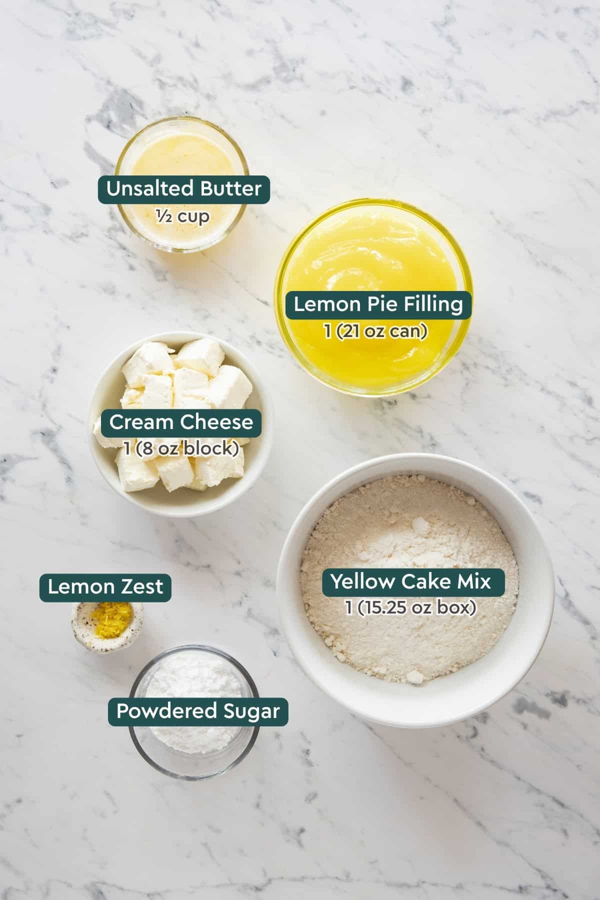 Ingredients for lemon cream cheese dump cake, including butter, lemon pie filling, cream cheese, cake mix, lemon zest, powdered sugar.
