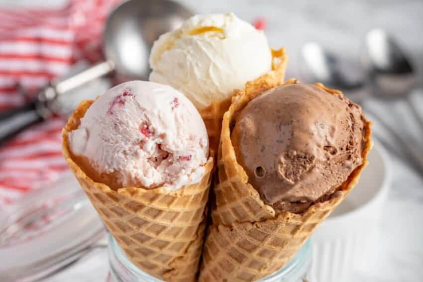 A bowl with three ice cream cones filled with vanilla, chocolate, and strawberry ice cream.