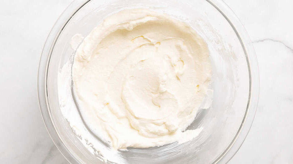 Overhead view of whipped cream in glass mixing bowl