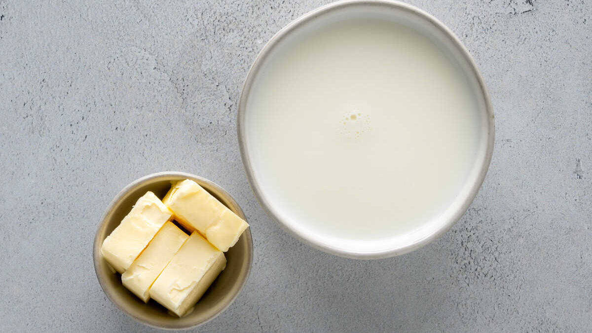 Milk and butter in bowls on a stone surface.