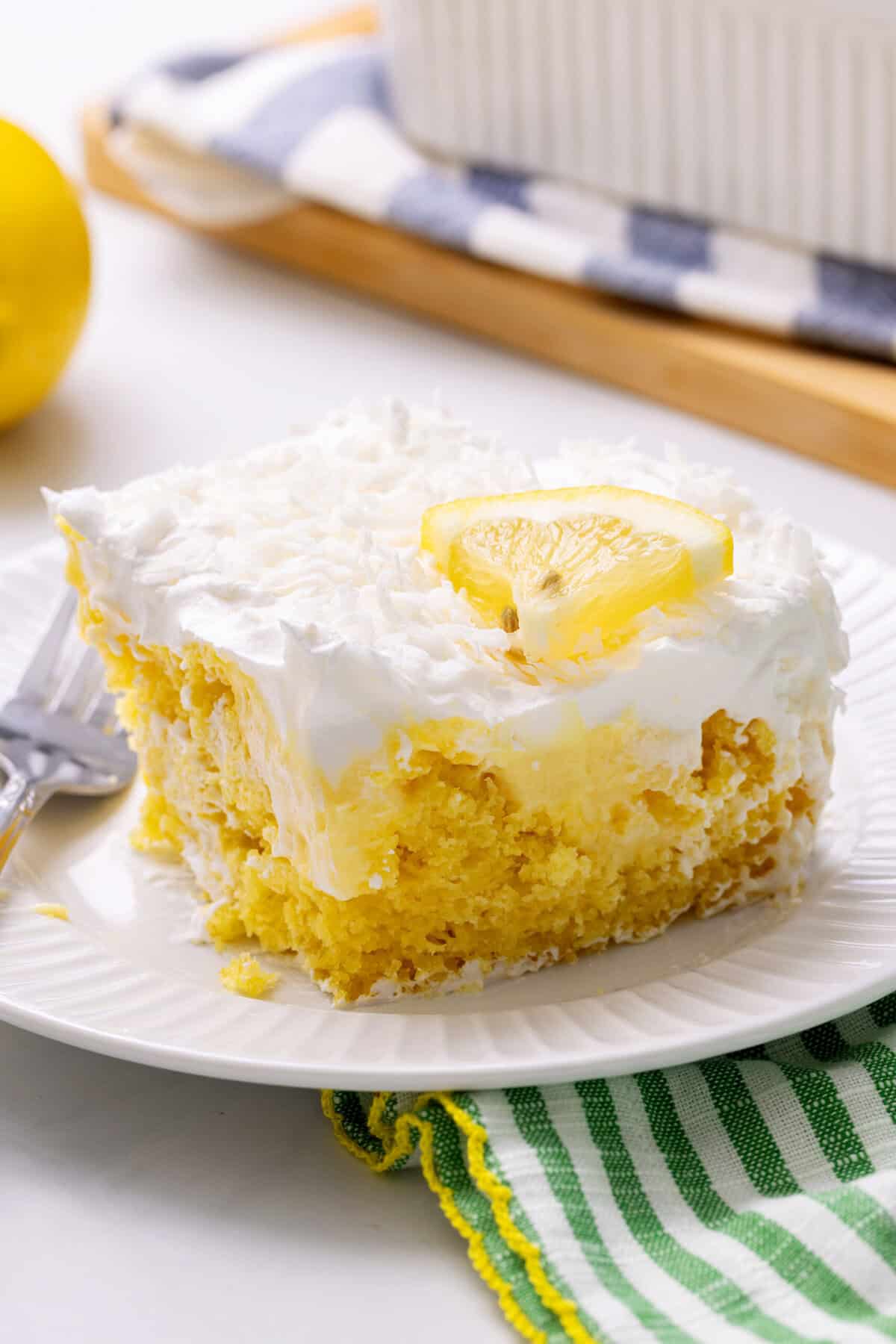 slice of lemon coconut poke cake served on a white round plate. 