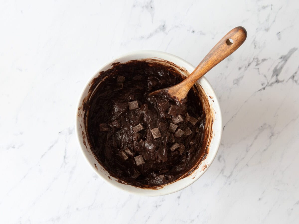 Chocolate chunks added to bowl of brownie batter.