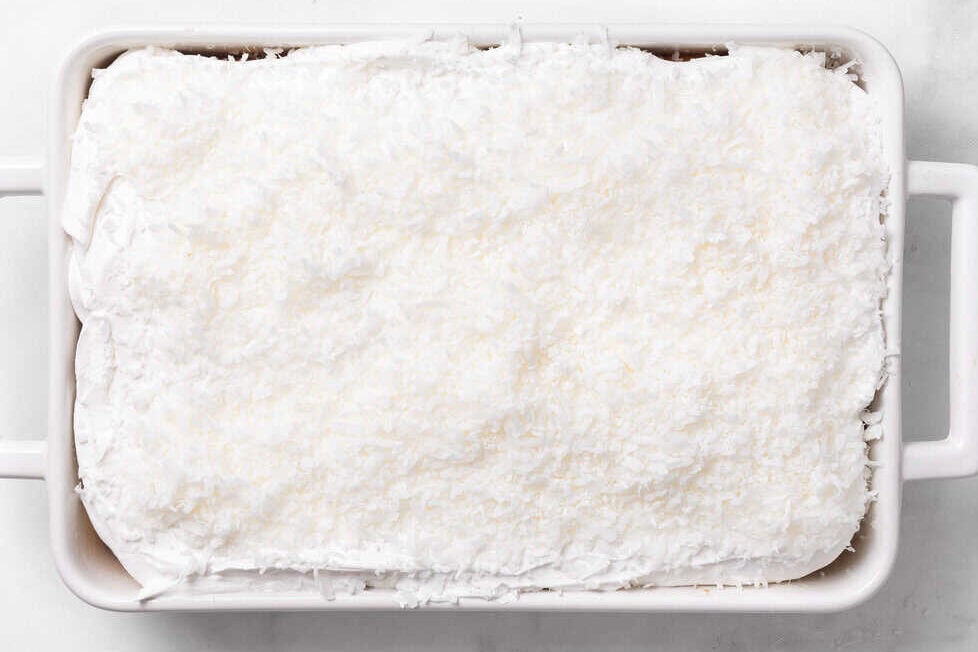 Shredded coconut sprinkled on top of coconut cake. 