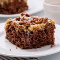 german chocolate poke cake slice on a white plate.