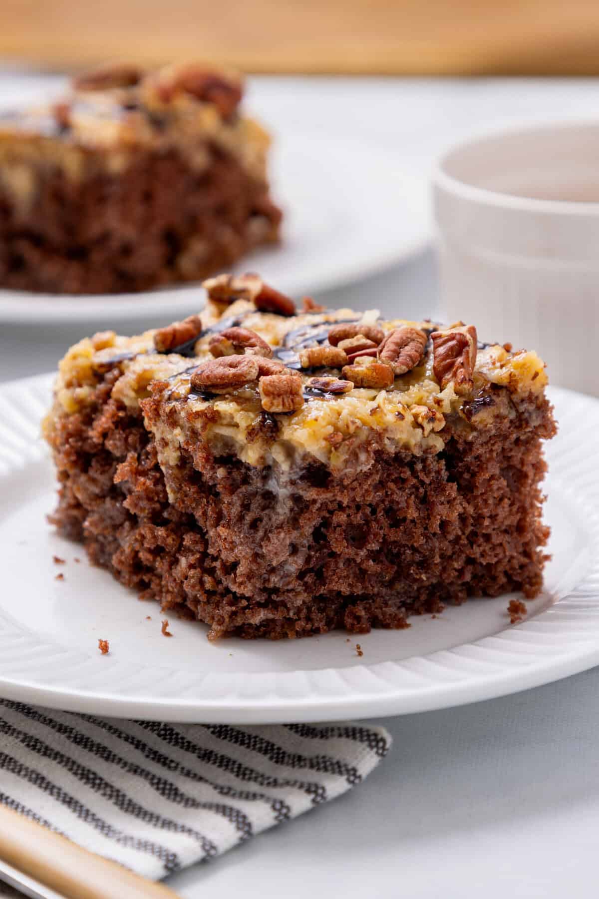 German chocolate poke cake slice on a white plate.
