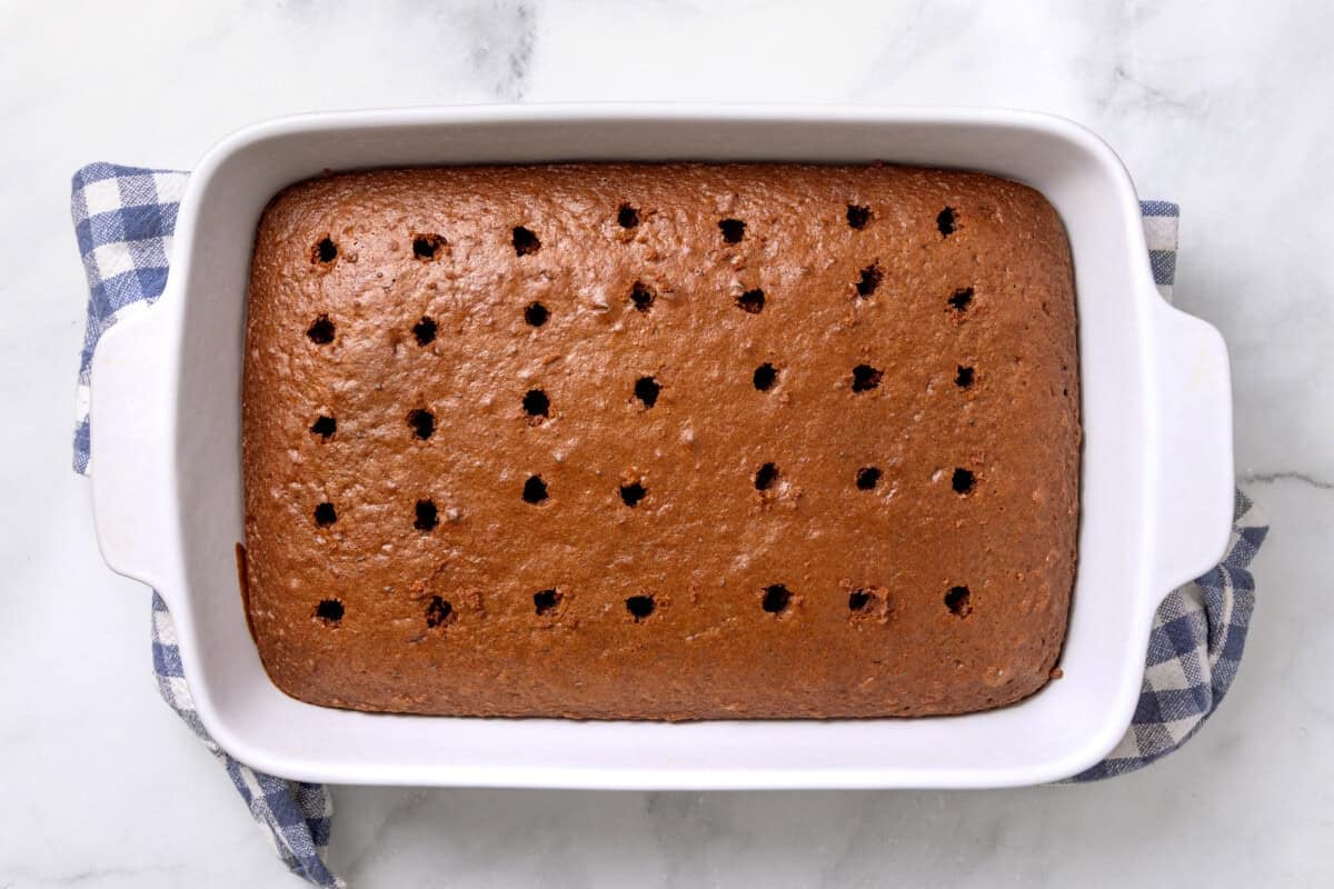 Chocolate cake in pan with holes poked in it.