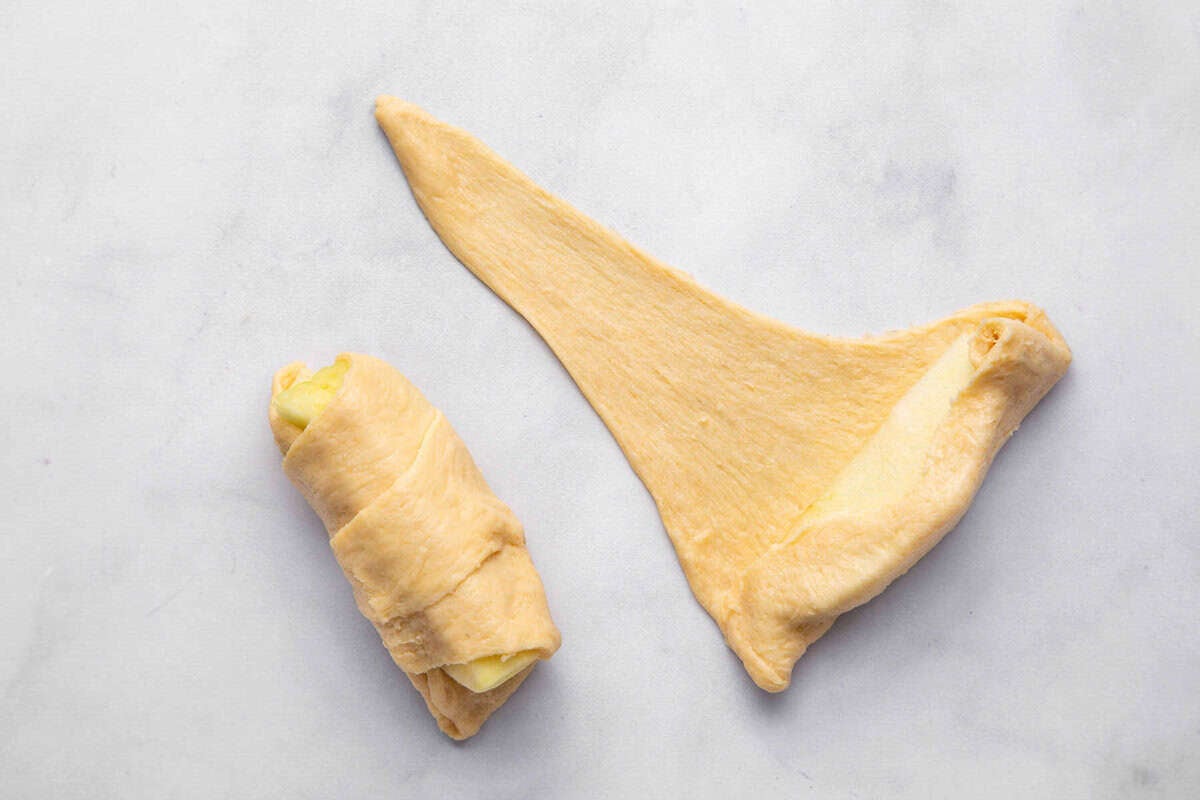 Apples being rolled up in crescent roll dough.