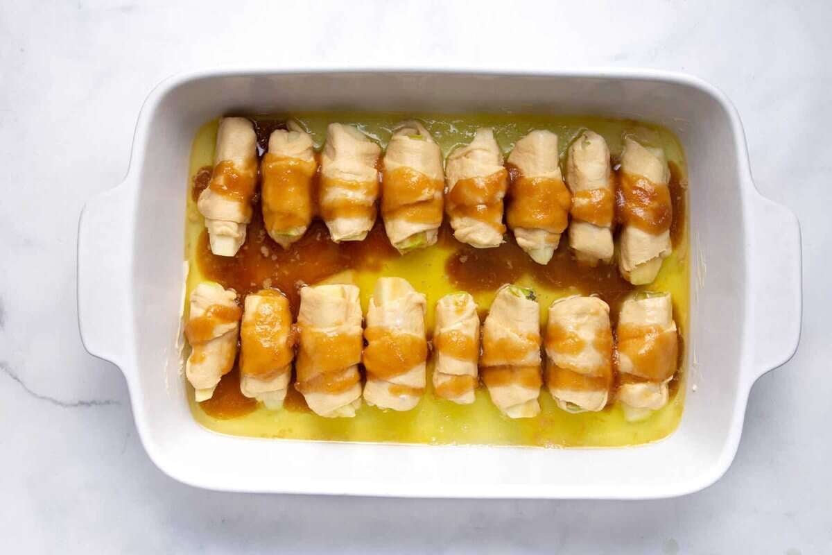 Apple dumplings in baking dish after adding Mountain Dew and cinnamon sauce.