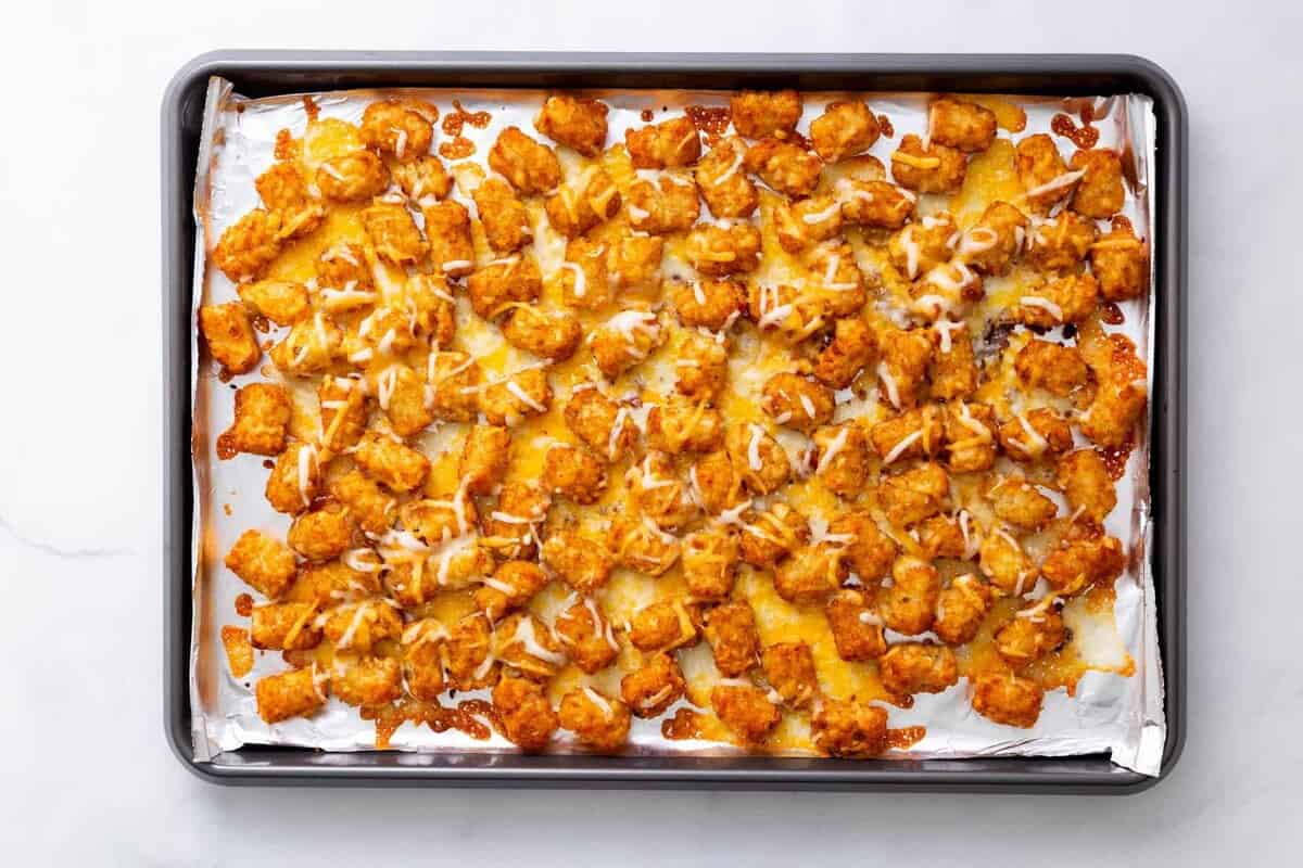 Step 3 to make loaded tater tots: melt shredded cheese in the oven over the pre-baked tater tots.