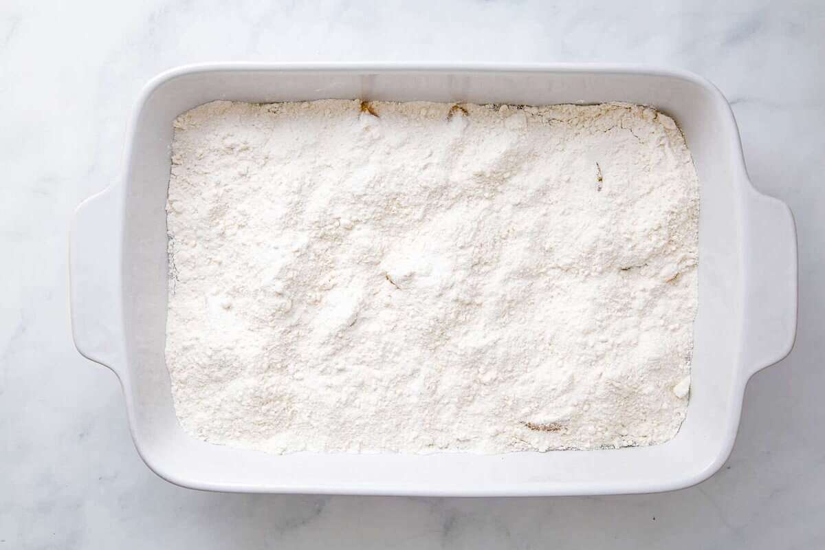 cake mix on top of peaches in a baking dish. 