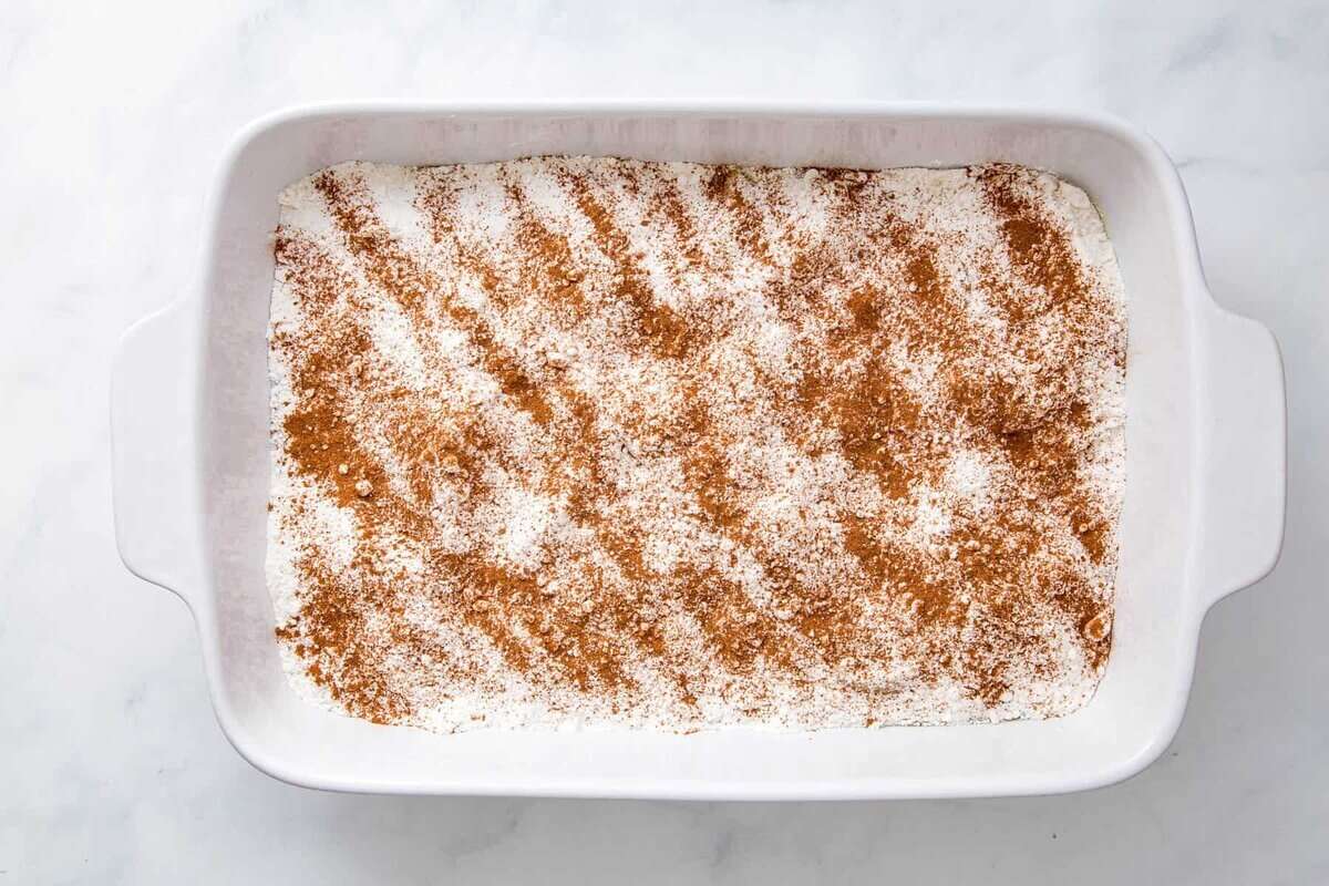 cinnamon on top of cake mix in a baking dish. 