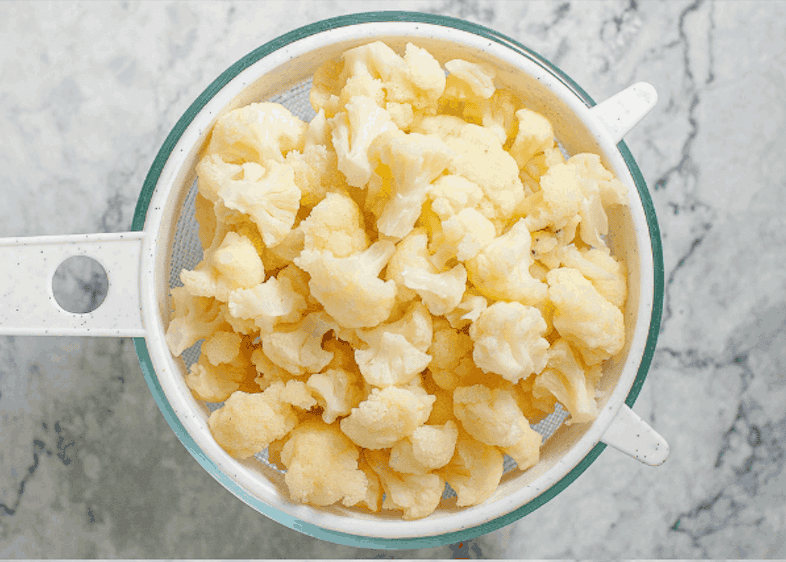 Blanched cauliflower in colander.