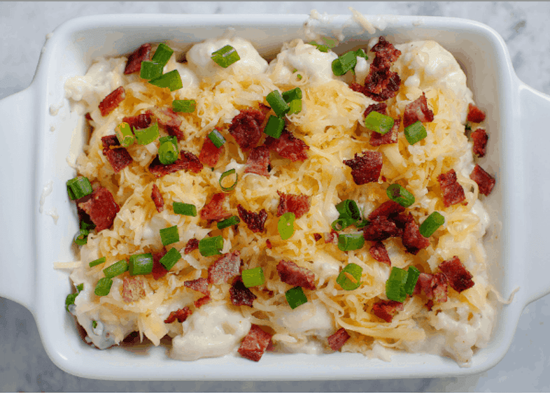 Cauliflower casserole with cheese, bacon, and green onions before baking.