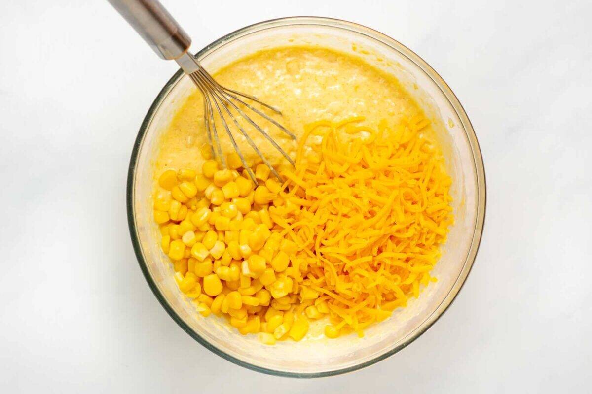 Ingredients for cornbread casserole in mixing bowl with whisk.