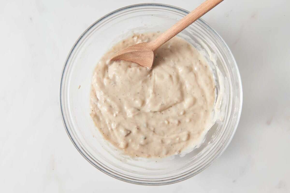 Mushroom soup sauce in bowl with wooden spoon.