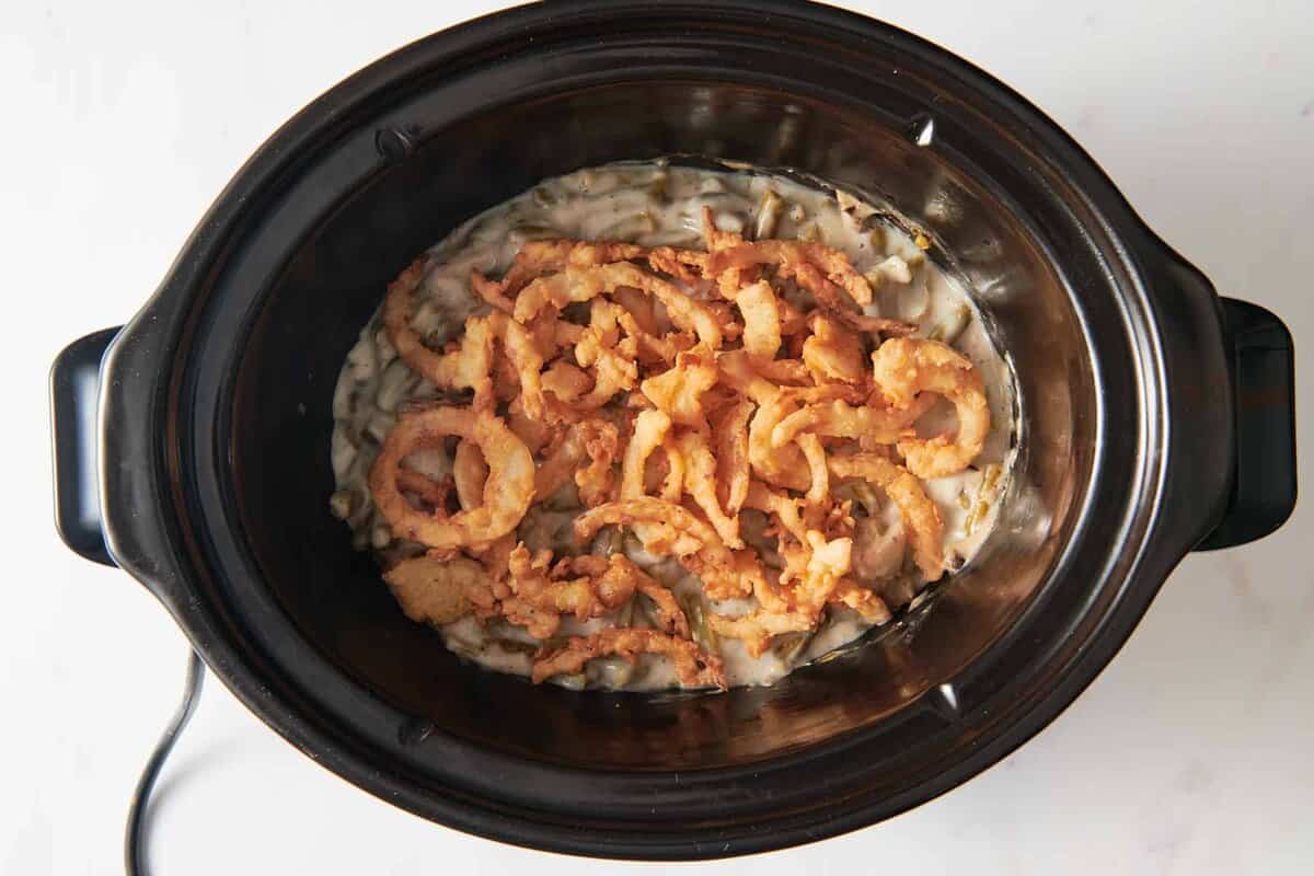 Green bean casserole in crockpot with crispy onion topping.