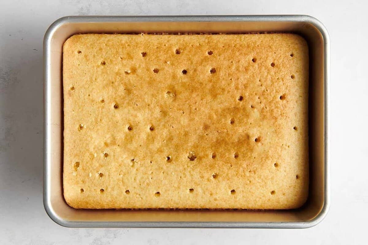 Cake baked in 9x13 pan poked with holes across the surface. 