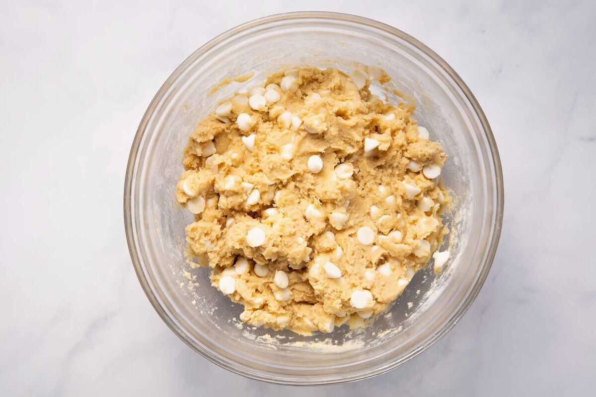 Banana pudding cookie dough with white chocolate chips in bowl.