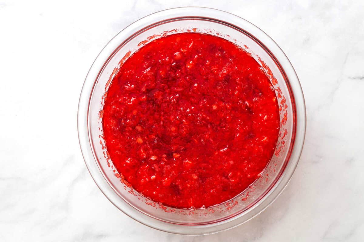 Cranberry jello salad with crushed pineapples in a glass bowl.
