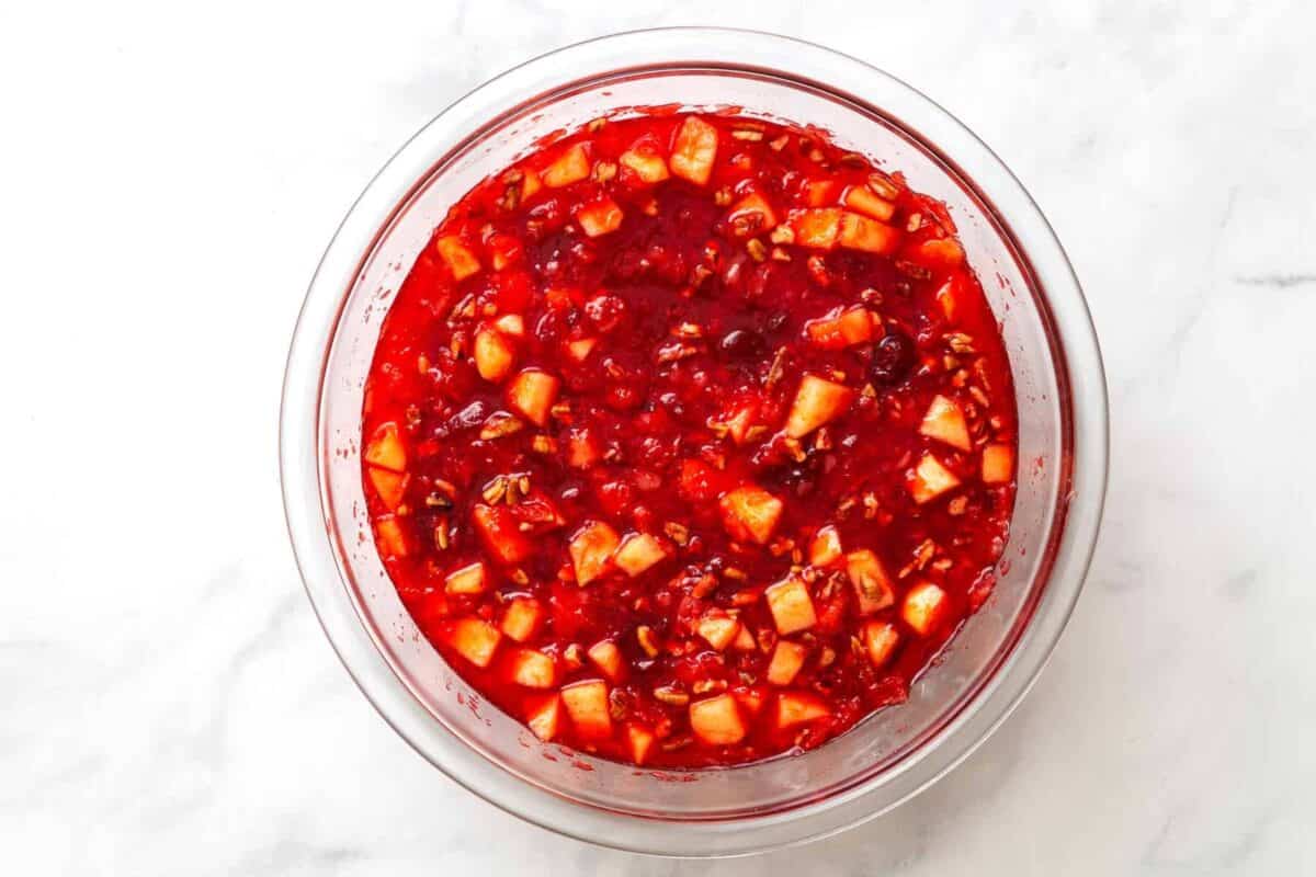 Cranberry jello salad with crushed pineapple and pecans in a glass bowl.