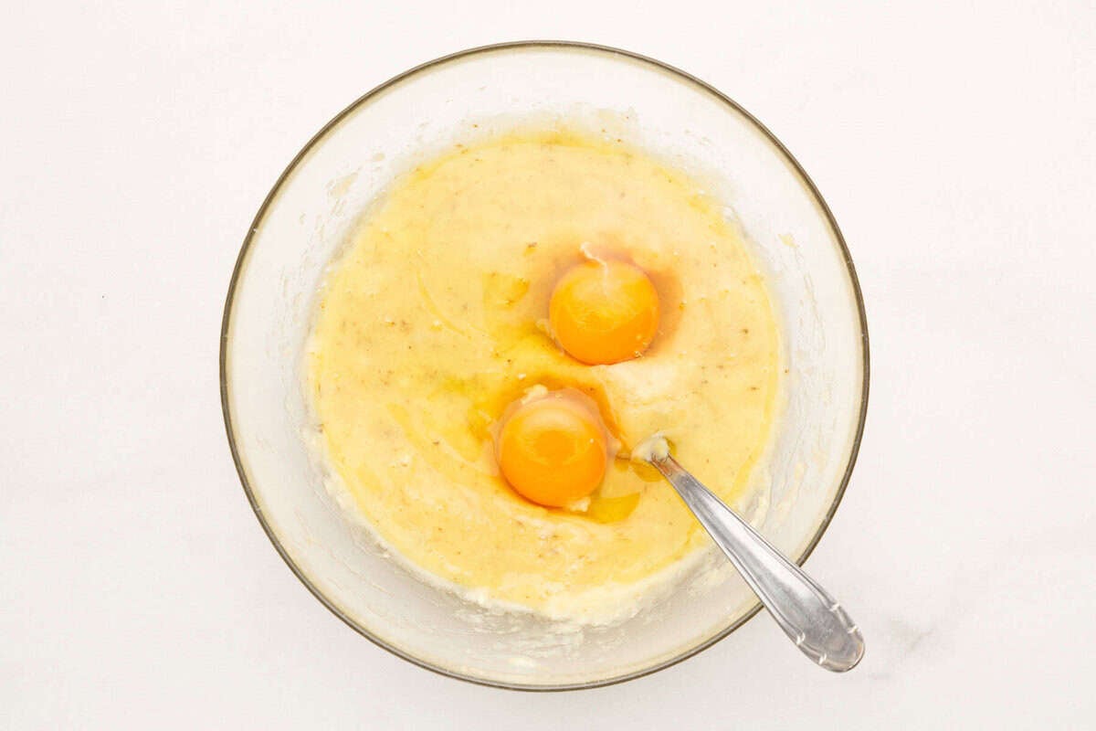 Two eggs added to mashed bananas to make banana bread batter.