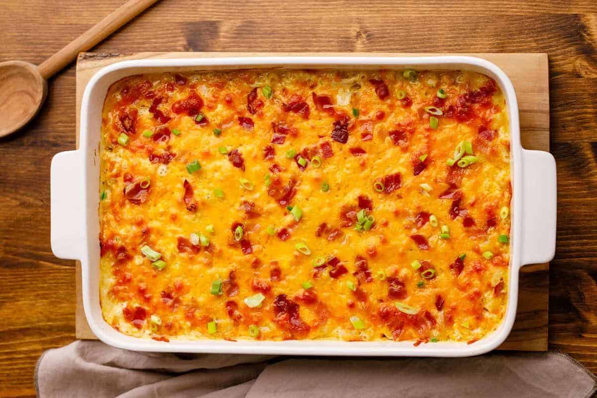 Crack chicken casserole in baking dish on wooden tabletop.
