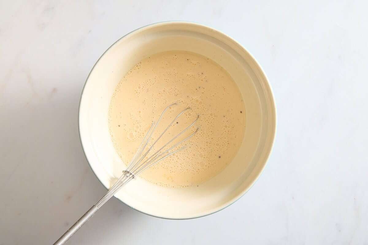 Egg mixture in bowl with whisk.