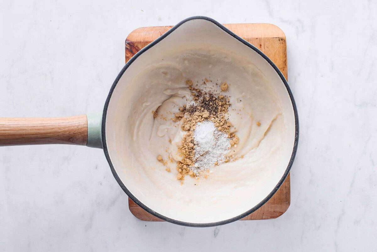 The sauce in the saucepan with the salt, pepper and dry mustard on top.