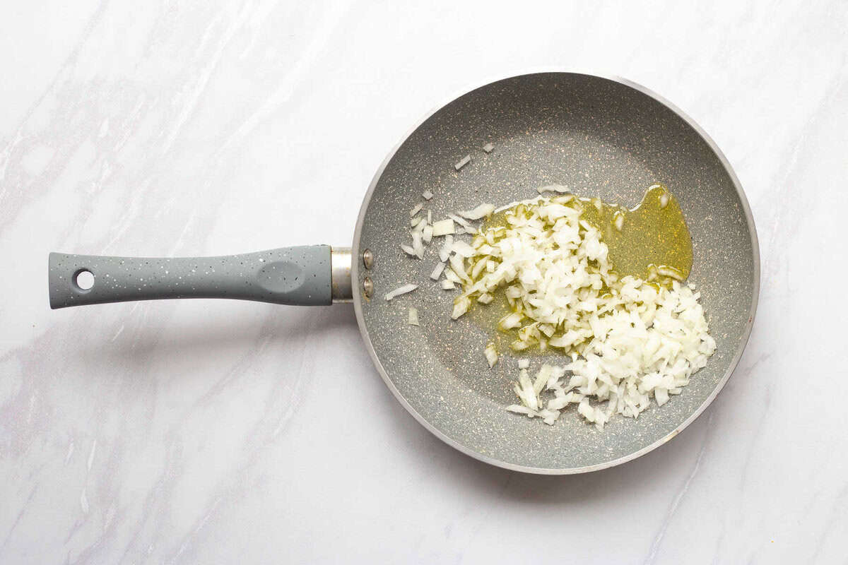 Onions and garlic added to skillet of oil.