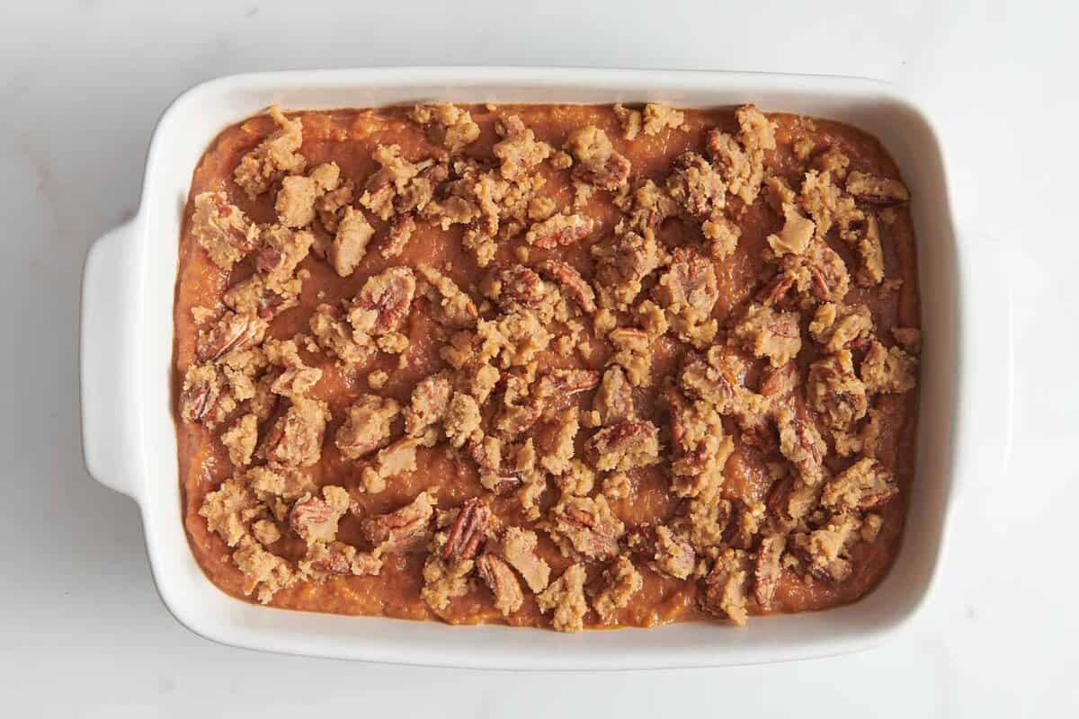 Pecan topping added to sweet potato souffle in baking dish.